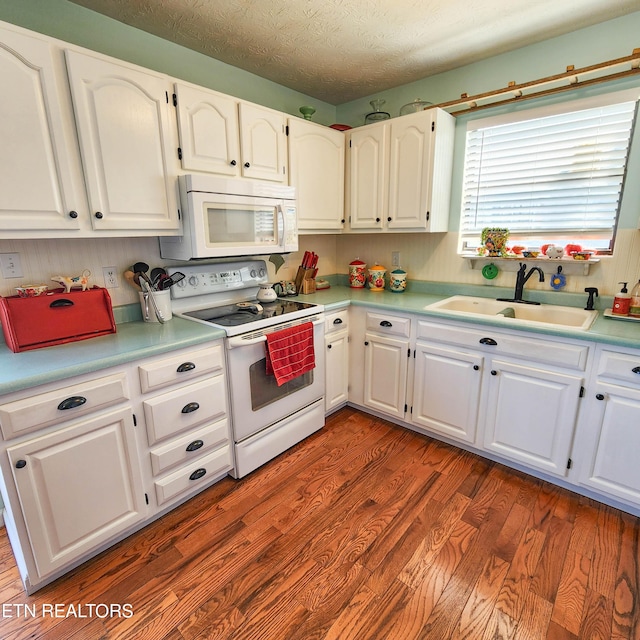 kitchen with white appliances, wood finished floors, a sink, white cabinetry, and light countertops