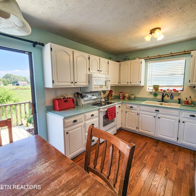 kitchen featuring wood finished floors, white appliances, a sink, and a wealth of natural light