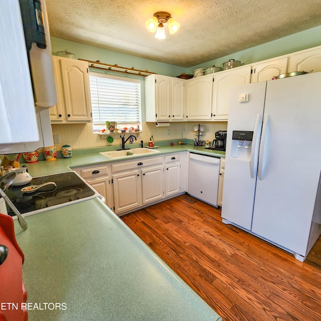 kitchen with a textured ceiling, white appliances, dark wood-type flooring, a sink, and white cabinetry