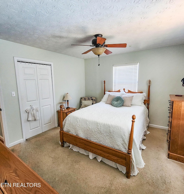 bedroom featuring light carpet, baseboards, a ceiling fan, a textured ceiling, and a closet