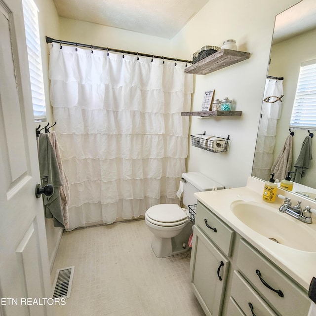 bathroom featuring toilet, a shower with shower curtain, vanity, and visible vents