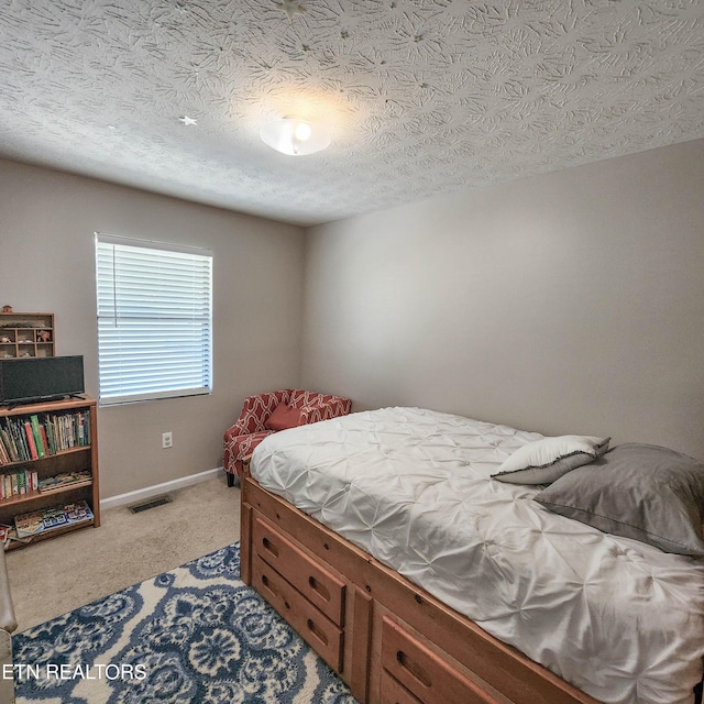 bedroom with baseboards, visible vents, a textured ceiling, and light colored carpet