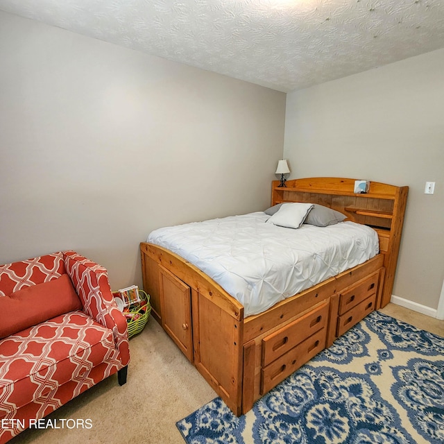 bedroom with light carpet, baseboards, and a textured ceiling