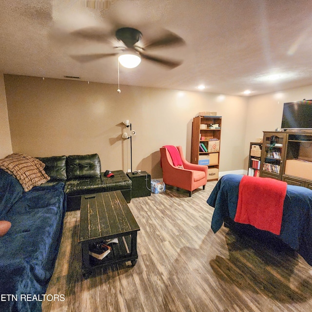 living room with visible vents, a textured ceiling, a ceiling fan, and wood finished floors