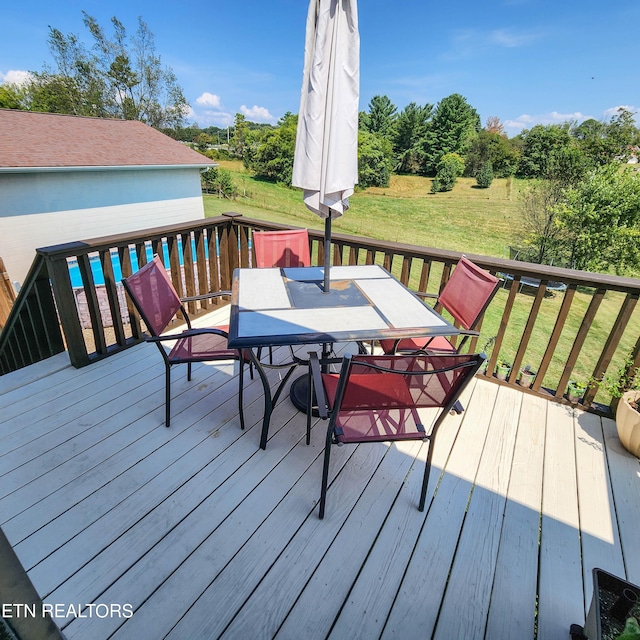 wooden deck featuring outdoor dining space and a lawn