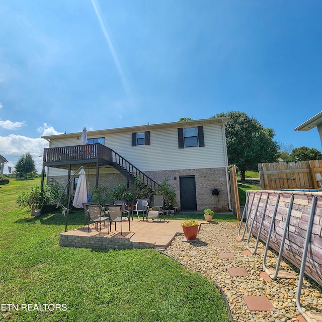 rear view of property with a yard, stairway, a patio area, and fence