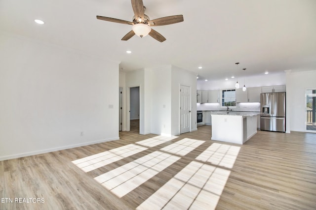 kitchen featuring stainless steel refrigerator with ice dispenser, ceiling fan, light wood-type flooring, decorative light fixtures, and a kitchen island