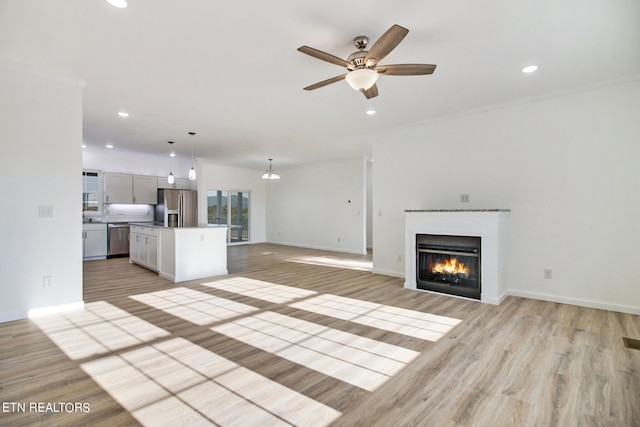 unfurnished living room with light wood-type flooring, ceiling fan, and crown molding