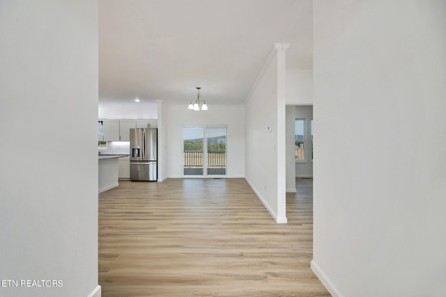 hall featuring light wood-type flooring, ornamental molding, and a chandelier