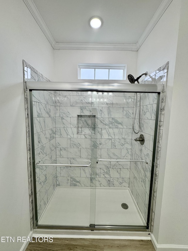 bathroom with a shower with shower door and ornamental molding