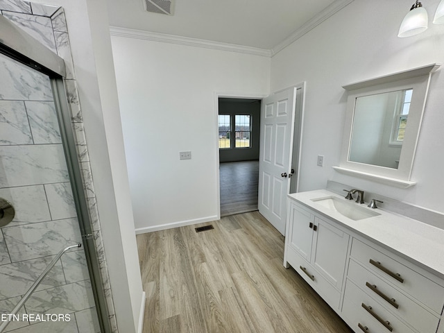 bathroom with french doors, hardwood / wood-style flooring, vanity, a shower with shower door, and ornamental molding