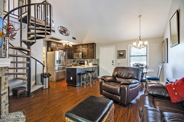 living room featuring sink, dark hardwood / wood-style floors, a stone fireplace, and a notable chandelier