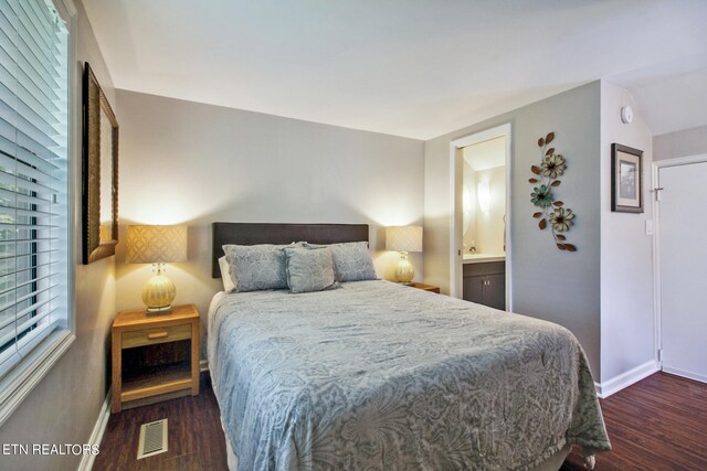 bedroom featuring multiple windows, connected bathroom, and dark hardwood / wood-style flooring