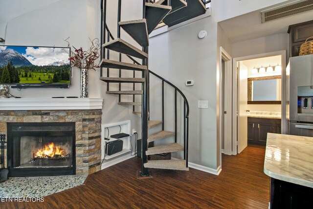 stairway with lofted ceiling, hardwood / wood-style floors, and a fireplace