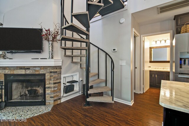 stairs with vaulted ceiling, a stone fireplace, and wood-type flooring