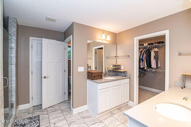 full bathroom with marble finish floor, baseboards, two vanities, and a sink