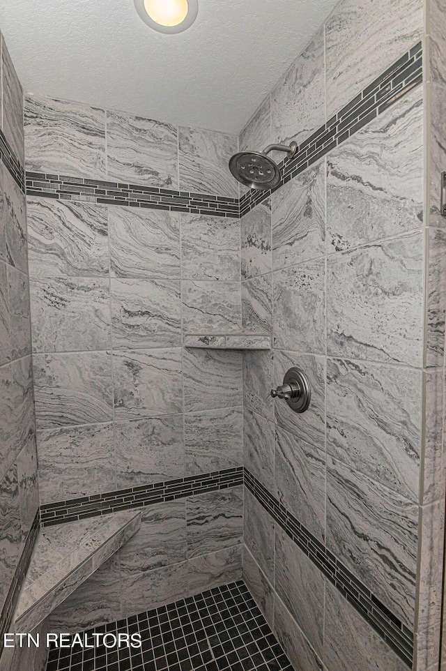 full bath with a textured ceiling and a tile shower