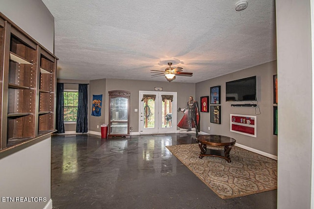 living area featuring a ceiling fan, a textured ceiling, baseboards, and finished concrete flooring