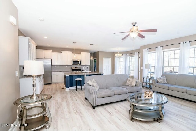 living room featuring light wood-type flooring, a ceiling fan, and recessed lighting