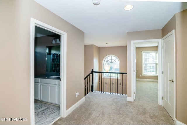 hallway with carpet floors, an upstairs landing, and baseboards