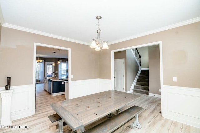 dining space with stairs, a notable chandelier, and wainscoting