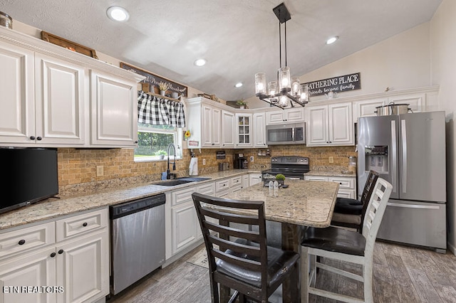 kitchen featuring white cabinets, appliances with stainless steel finishes, sink, lofted ceiling, and decorative backsplash