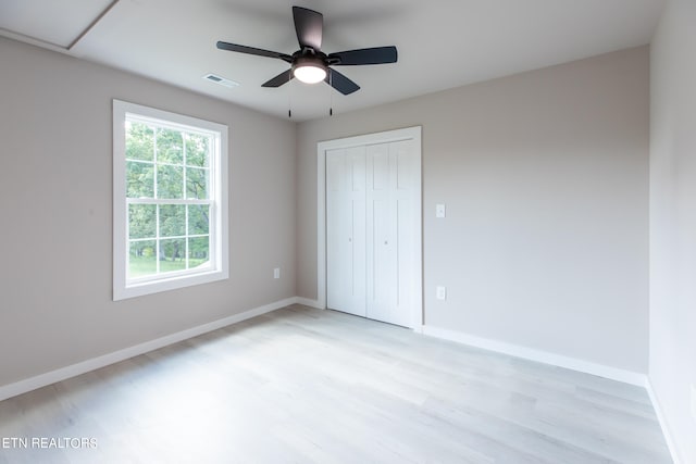 unfurnished bedroom featuring light wood-type flooring, ceiling fan, a closet, and multiple windows