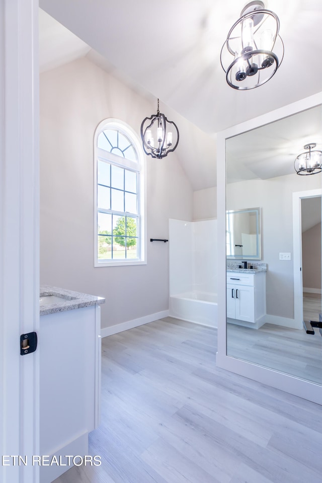 walk in closet with vaulted ceiling, a notable chandelier, and light hardwood / wood-style flooring