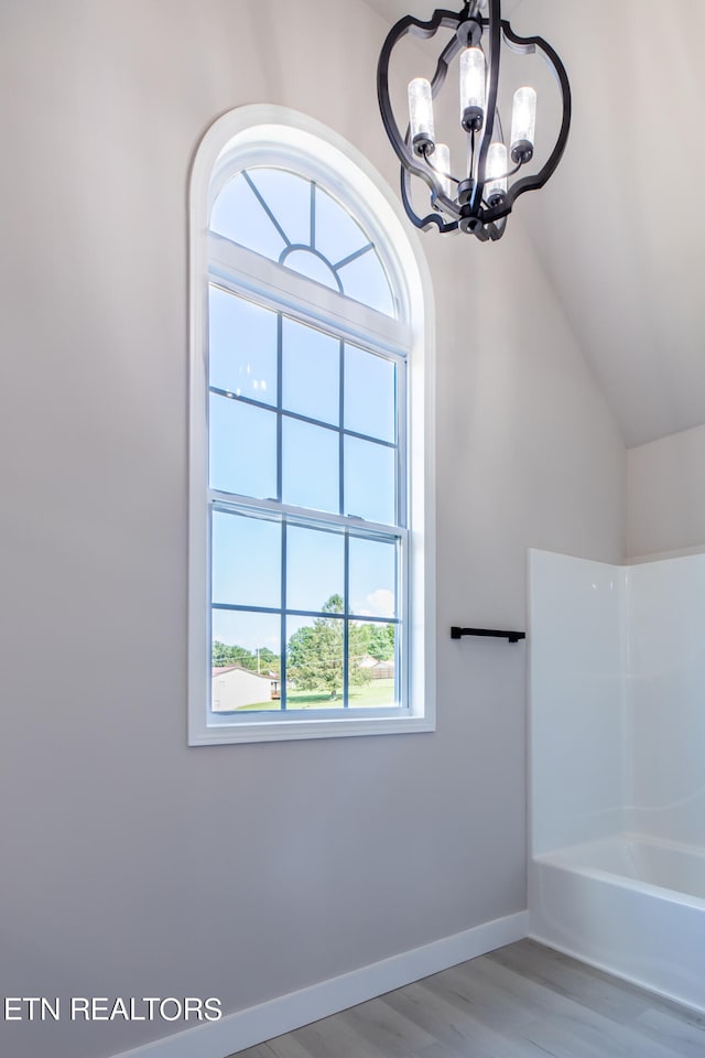 bathroom featuring a shower, vaulted ceiling, an inviting chandelier, and wood-type flooring