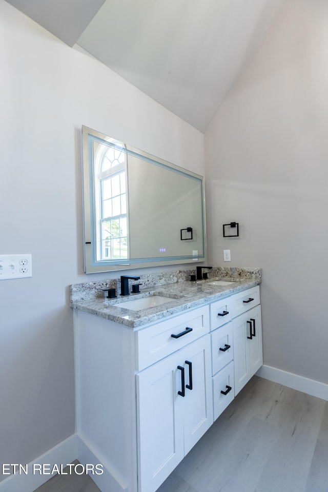 bathroom with hardwood / wood-style flooring, vanity, and lofted ceiling