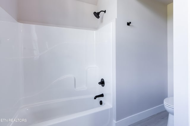 bathroom featuring bathtub / shower combination, hardwood / wood-style floors, and toilet