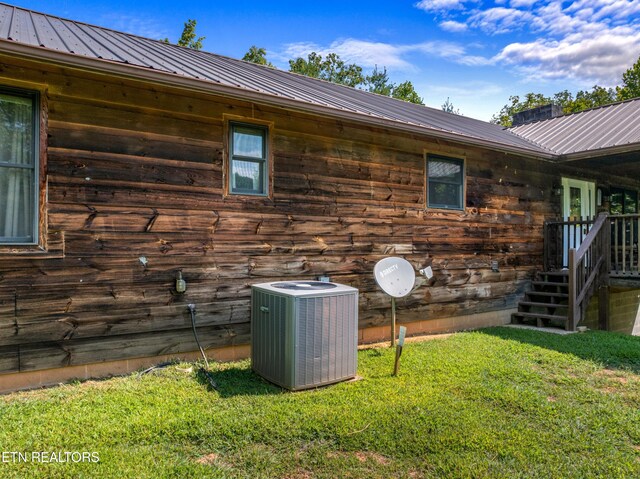 view of side of property featuring a lawn and central air condition unit