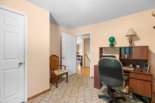 home office featuring a textured ceiling and light colored carpet