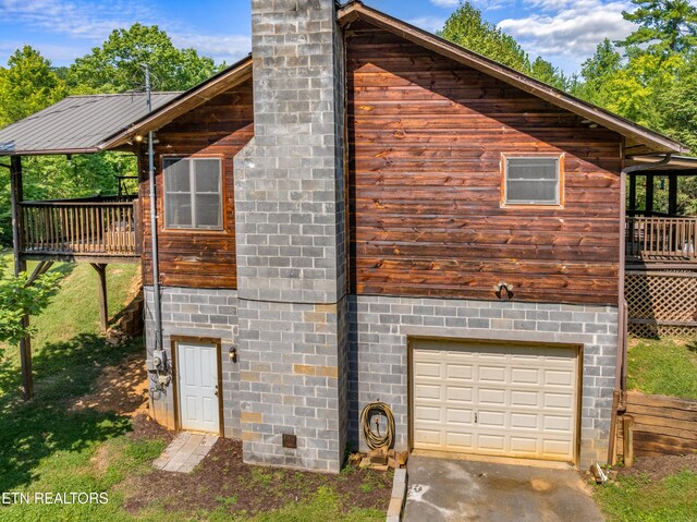 view of property exterior featuring a garage and a deck