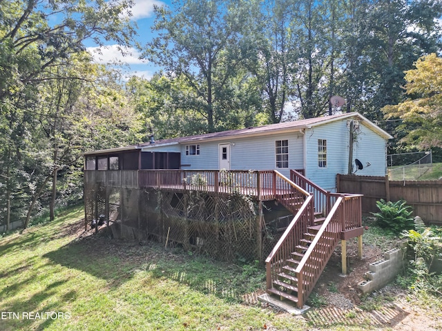 rear view of property with a sunroom, a yard, and a wooden deck