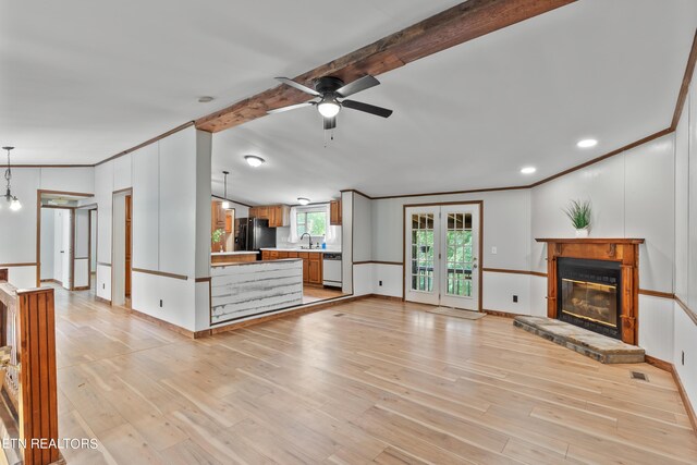 unfurnished living room featuring a stone fireplace, sink, beamed ceiling, and light hardwood / wood-style floors