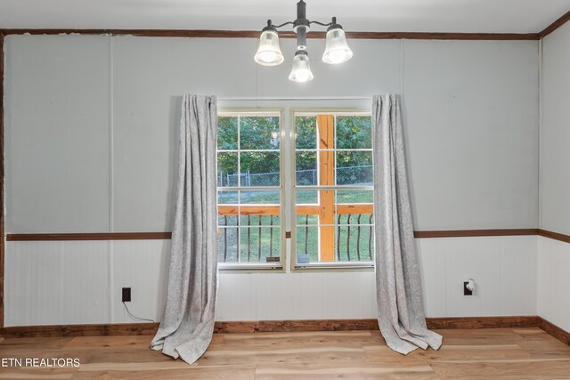 empty room featuring a notable chandelier and light hardwood / wood-style flooring