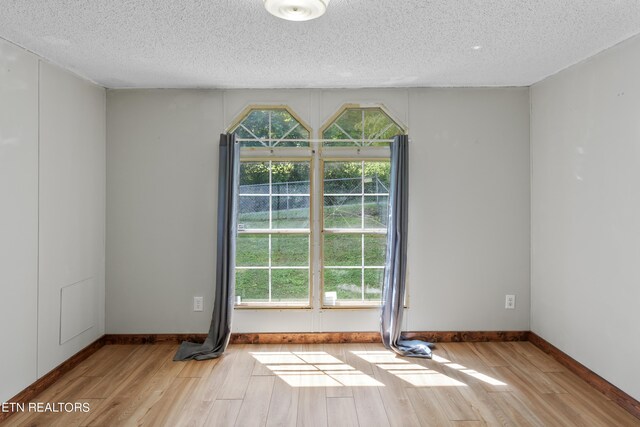 spare room with light hardwood / wood-style floors and a textured ceiling