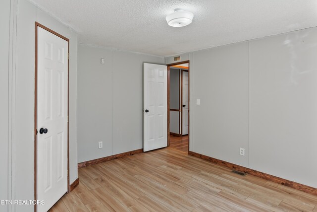 unfurnished bedroom with a textured ceiling and light hardwood / wood-style flooring