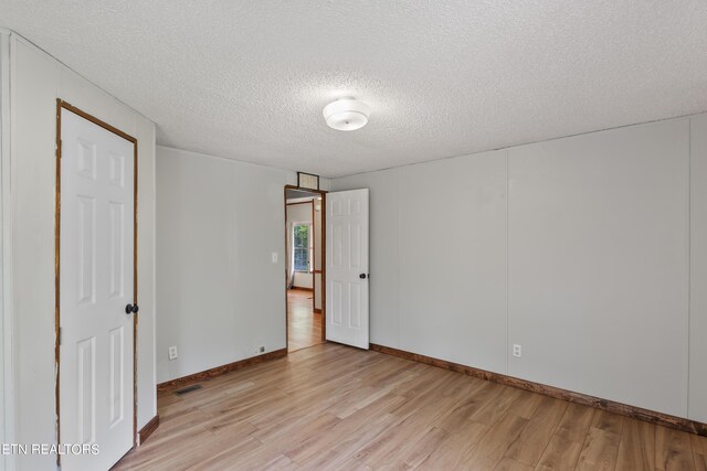 unfurnished room with a textured ceiling and light hardwood / wood-style floors