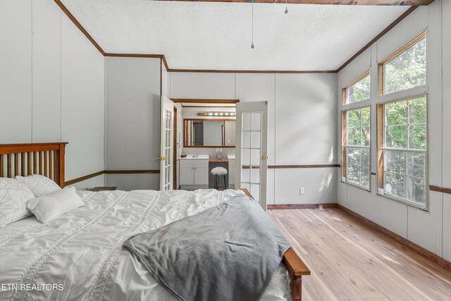 bedroom with light hardwood / wood-style floors, sink, a textured ceiling, and ensuite bath