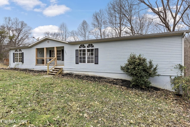 rear view of property featuring a porch and a yard