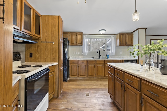 kitchen with black refrigerator, white range with electric stovetop, sink, decorative light fixtures, and light hardwood / wood-style floors