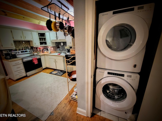 washroom featuring stacked washer / drying machine, sink, and light hardwood / wood-style floors