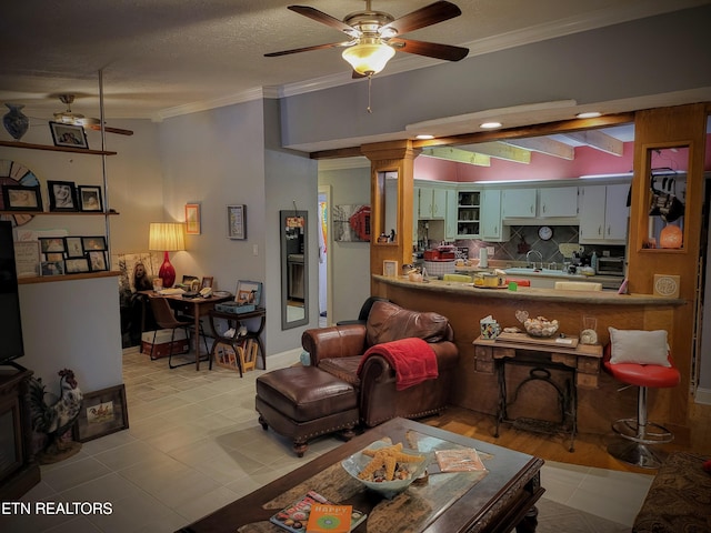 living room with a textured ceiling, crown molding, ceiling fan, and sink