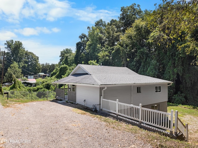 exterior space featuring driveway, a porch, and fence