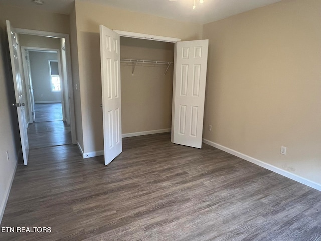 unfurnished bedroom with a closet and dark wood-type flooring