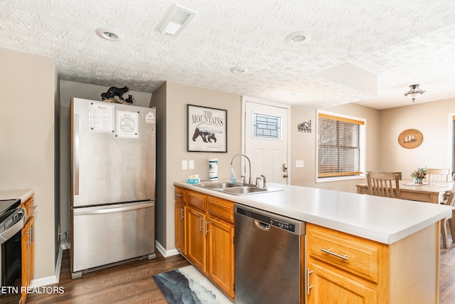 kitchen with dark hardwood / wood-style floors, appliances with stainless steel finishes, sink, kitchen peninsula, and a textured ceiling