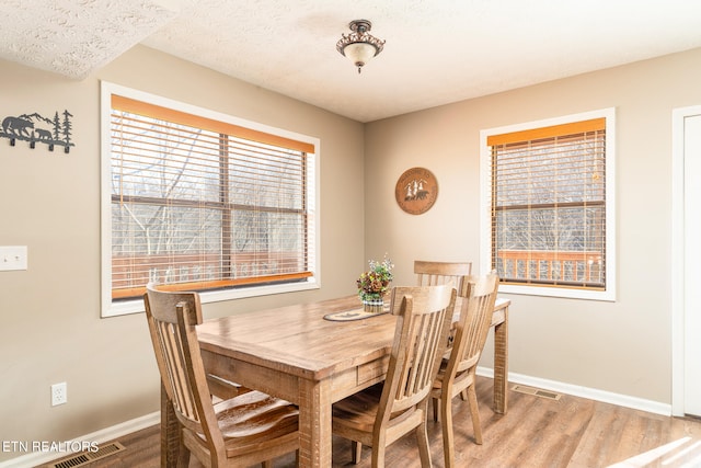 dining room with wood-type flooring and a textured ceiling