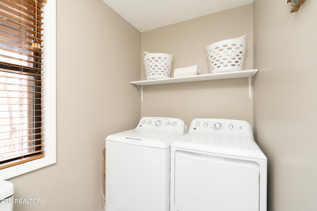 laundry area featuring plenty of natural light, a textured ceiling, and independent washer and dryer